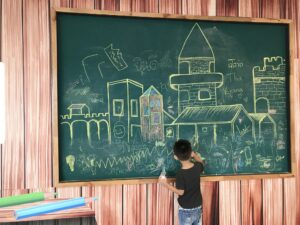 Kid is drawing on the board. Creativity. Smart children.
